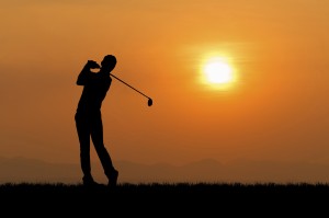 Silhouette of golfer against sunset